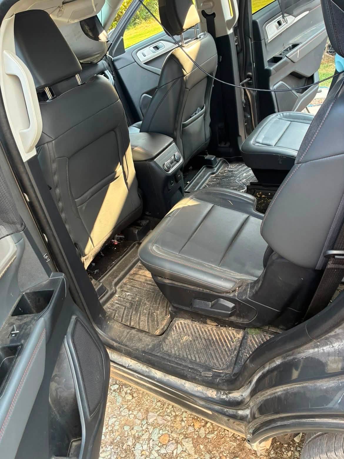 Second row of a Ford Explorer before detailing, with debris and red dirt on the carpet and seats