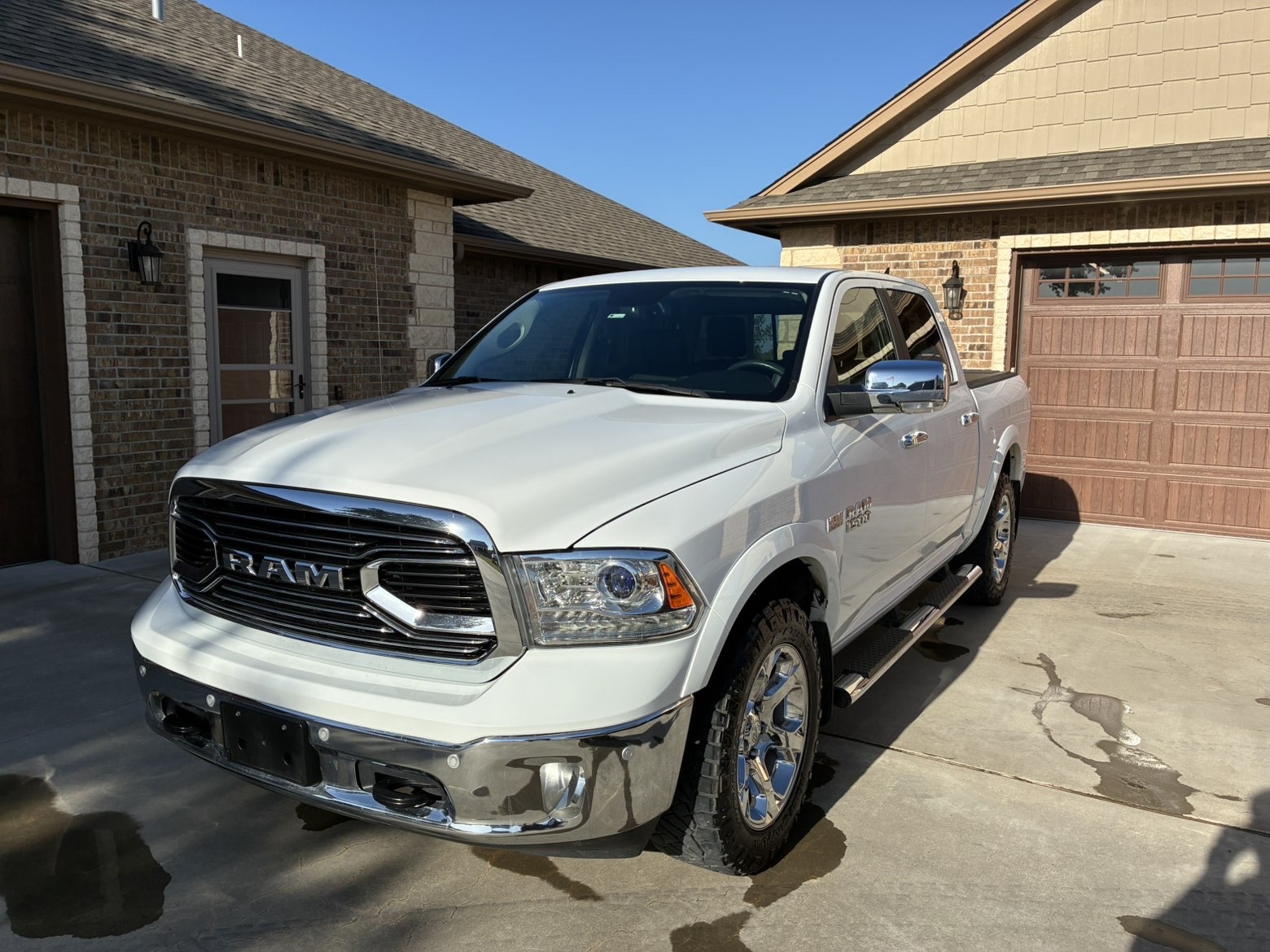 Freshly detailed white Ram 1500 truck with polished chrome grille in a driveway
